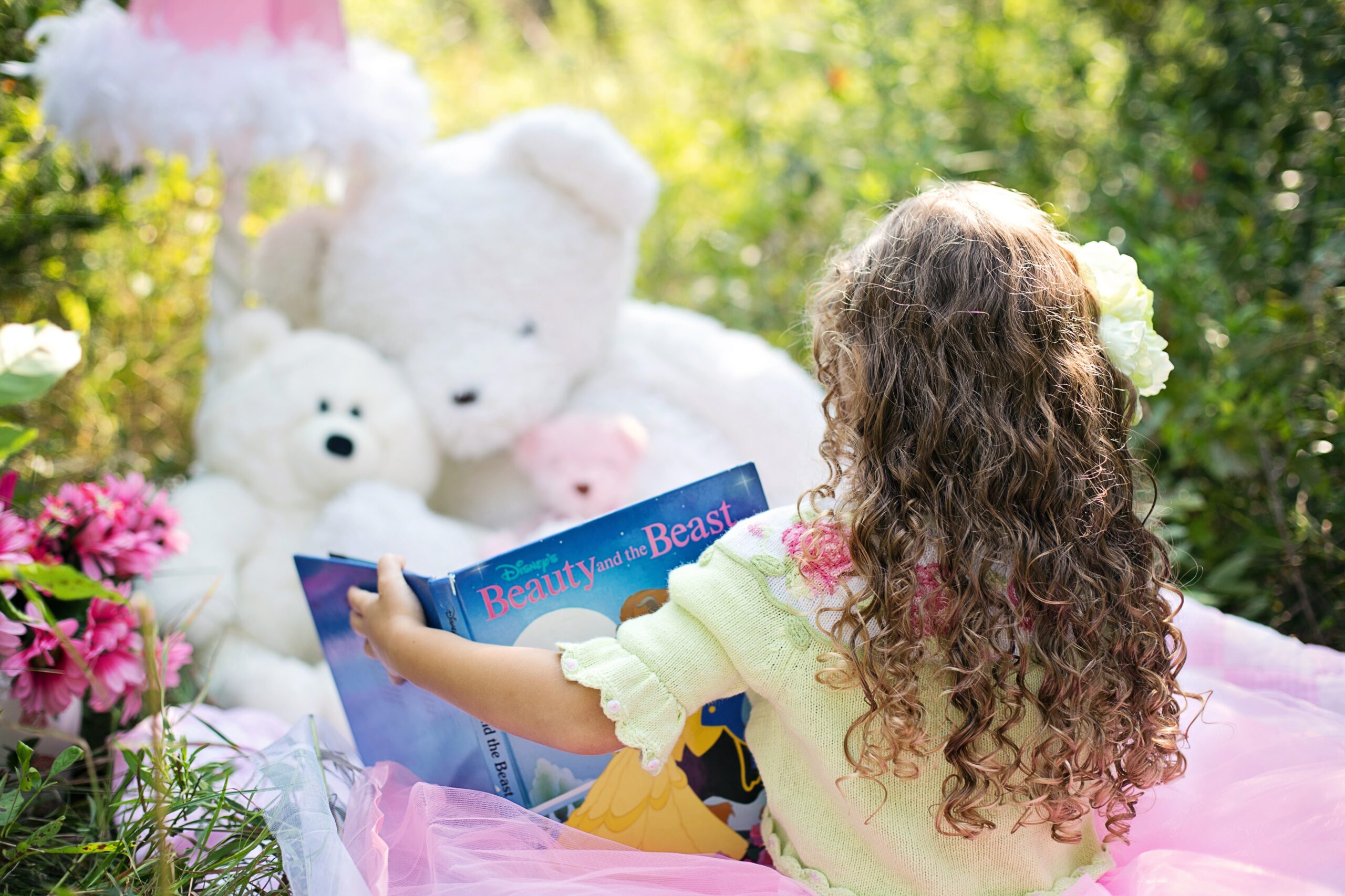 Girl reading to her stuffed animals outside