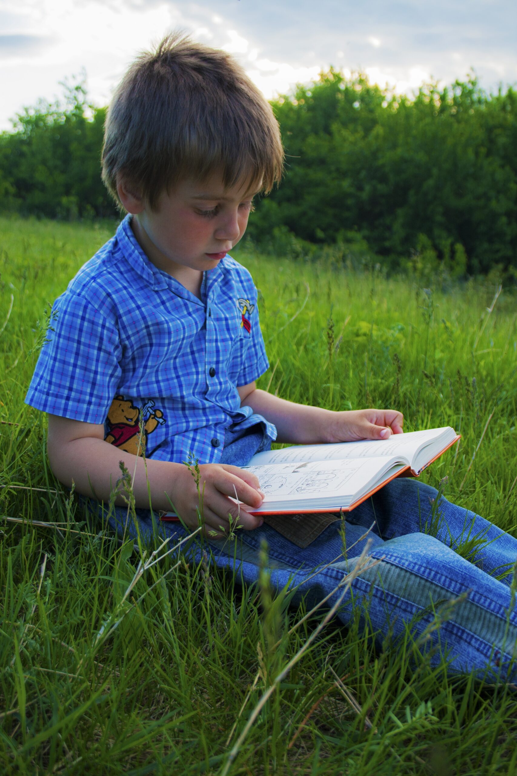 Boy reading a book outside